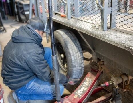 Person reparerer tilhenger ved hjulet med en jekk